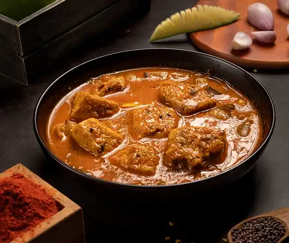 Tangy South Indian mango fish kulambu cooked with fresh seafood dishes and traditional spices.